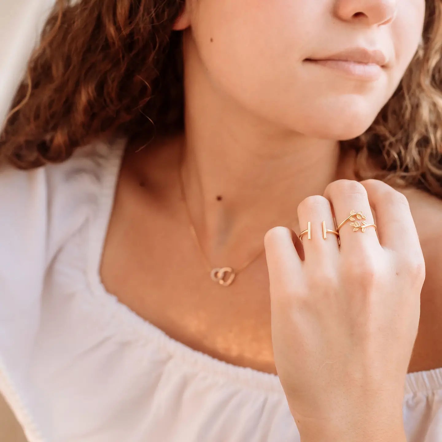 Close-up of a person wearing gold jewelry including a necklace and ring.