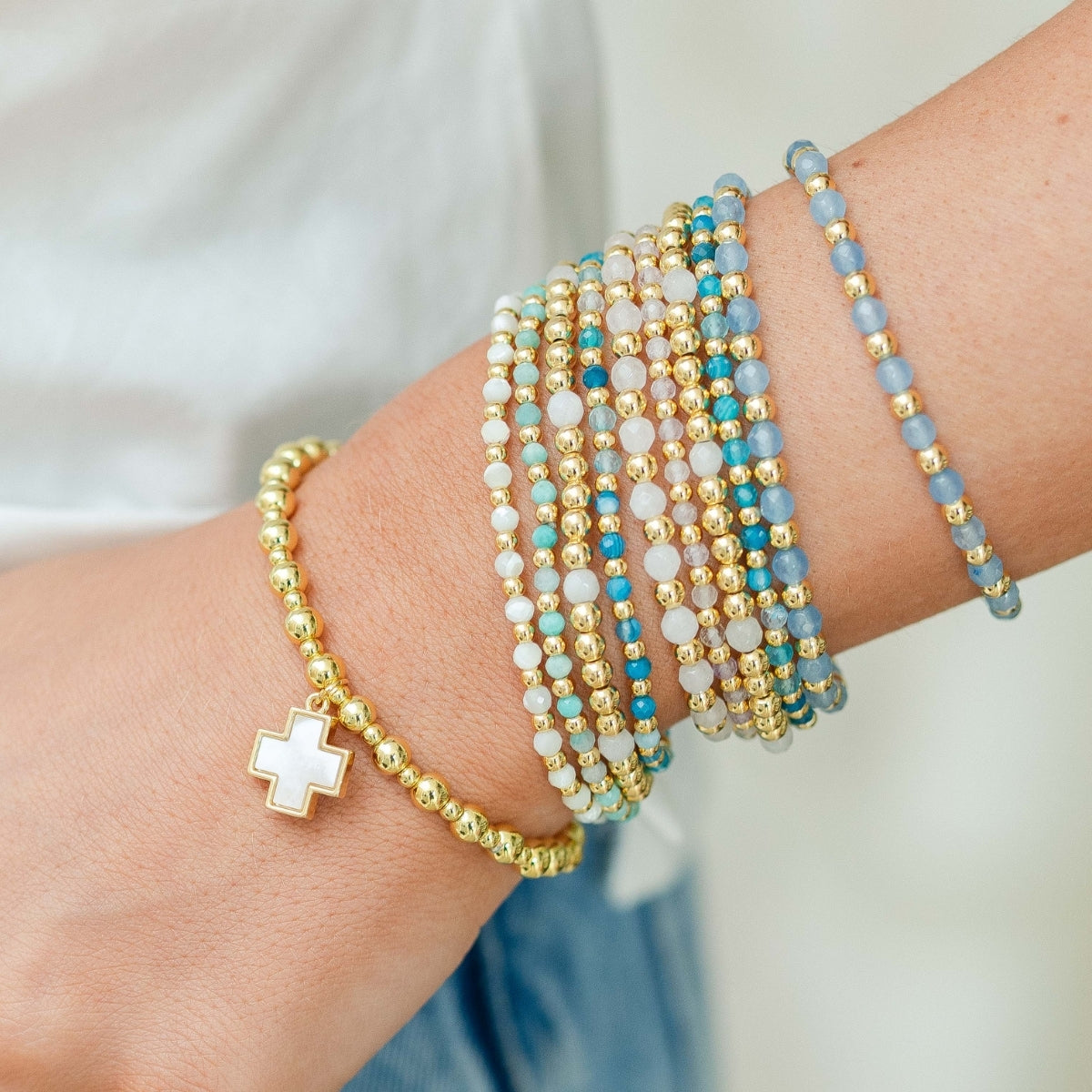 Multiple beaded bracelets on a wrist with a neutral background