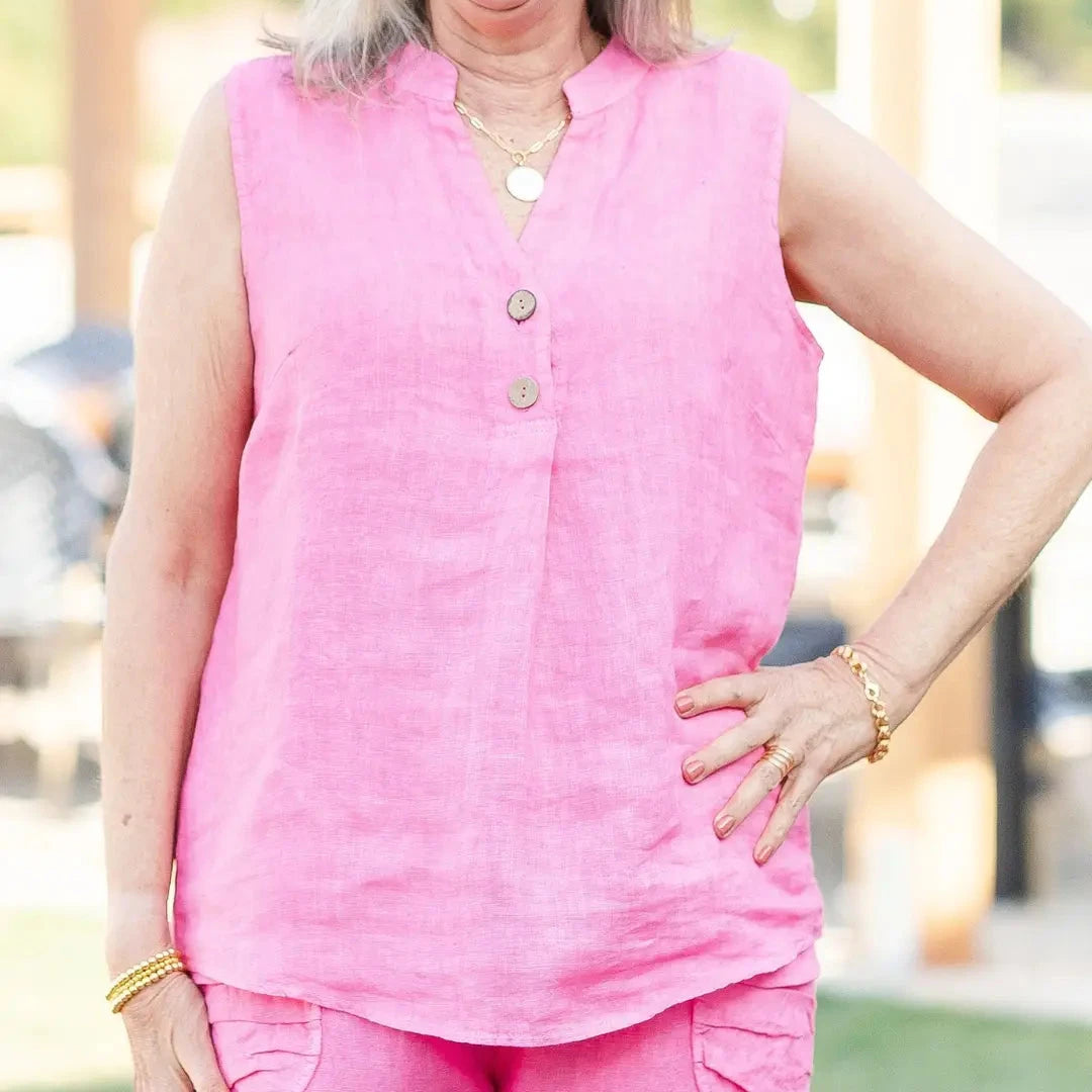 Person wearing a pink sleeveless top with buttons, standing outdoors.