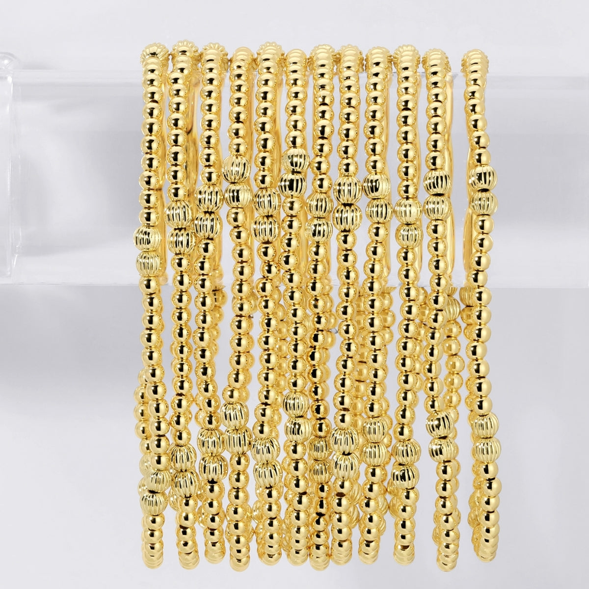 Gold beaded bracelets on a white background