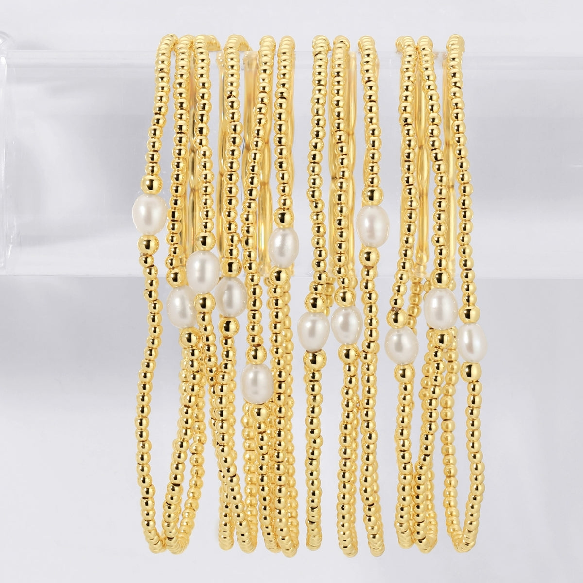Gold beaded bracelets with pearls on a white background