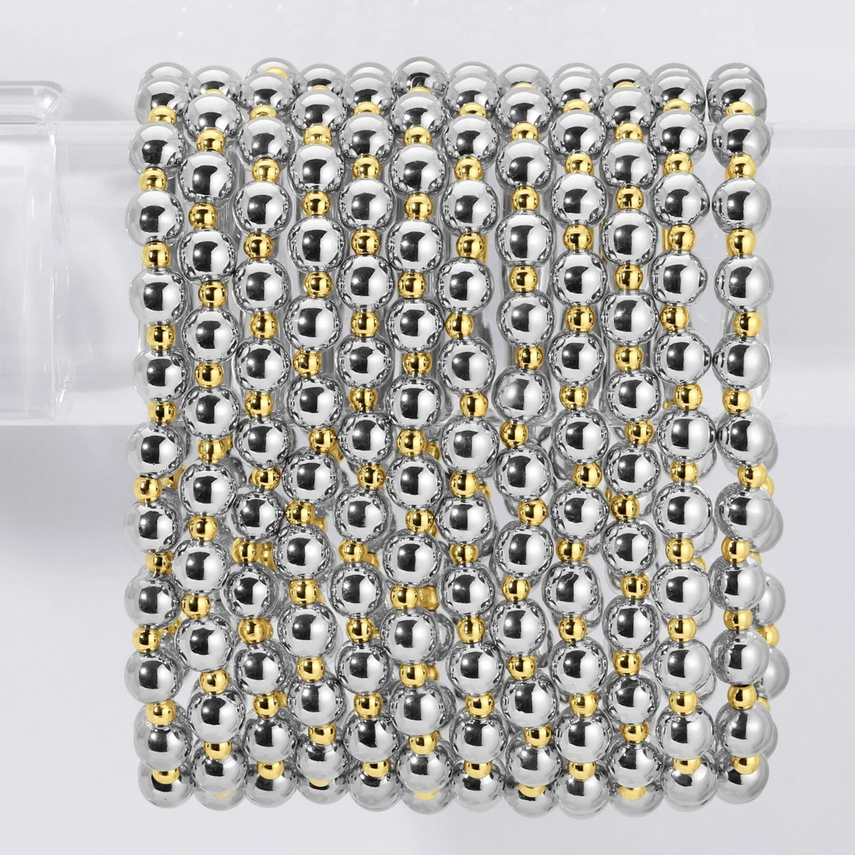Stack of silver and gold beaded bracelets on a white background