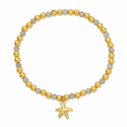 Bracelet with gold beads and a starfish charm on a white background