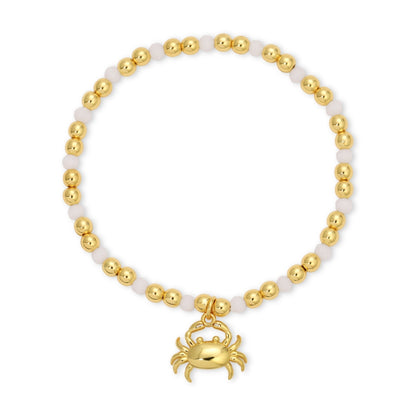 Bracelet with gold beads and a crab charm on a white background