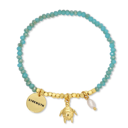 Bracelet with turquoise beads, gold charm, and turtle pendant on a white background
