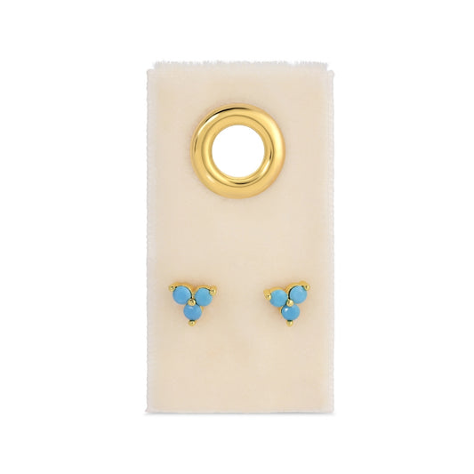 Gold and turquoise earrings on a beige card with a white background