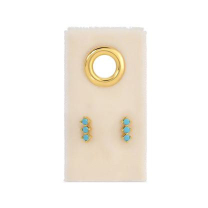 Gold and turquoise earrings on a white card with a gold ring design.