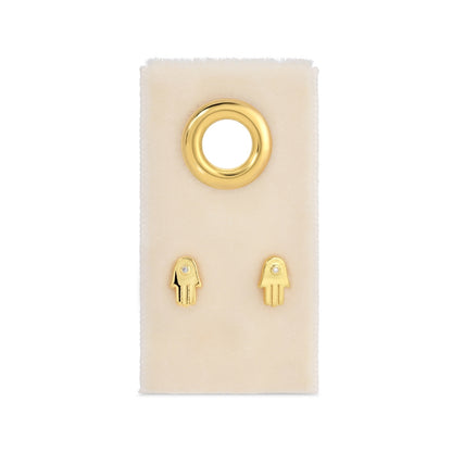 Gold hamsa hand earrings on a white card with a white background