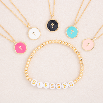 Necklaces with various pendants and a 'BLESSED' bracelet on a light background