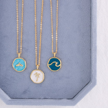 Three gold necklaces with unique pendants on a blue display box.