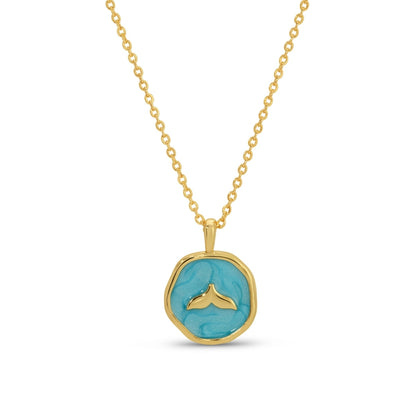 Gold necklace with a turquoise pendant featuring a whale tail design on a white background
