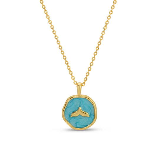 Gold necklace with a turquoise pendant featuring a whale tail design on a white background