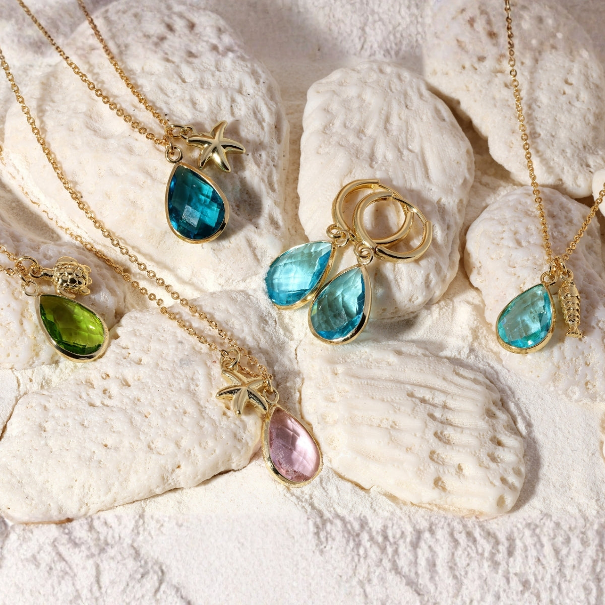 Gold necklaces with colorful gemstones on a textured white surface
