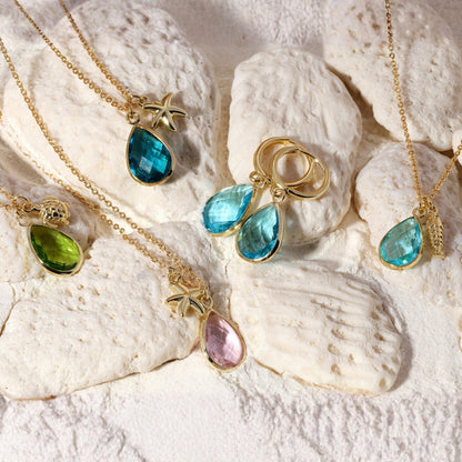 Gold necklaces with colorful gemstones on a textured white surface