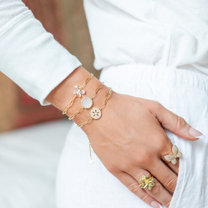 Gold bracelet and ring on a hand against a white background
