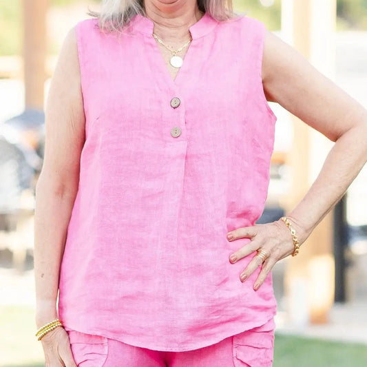 Person wearing a pink sleeveless top with buttons, standing outdoors.